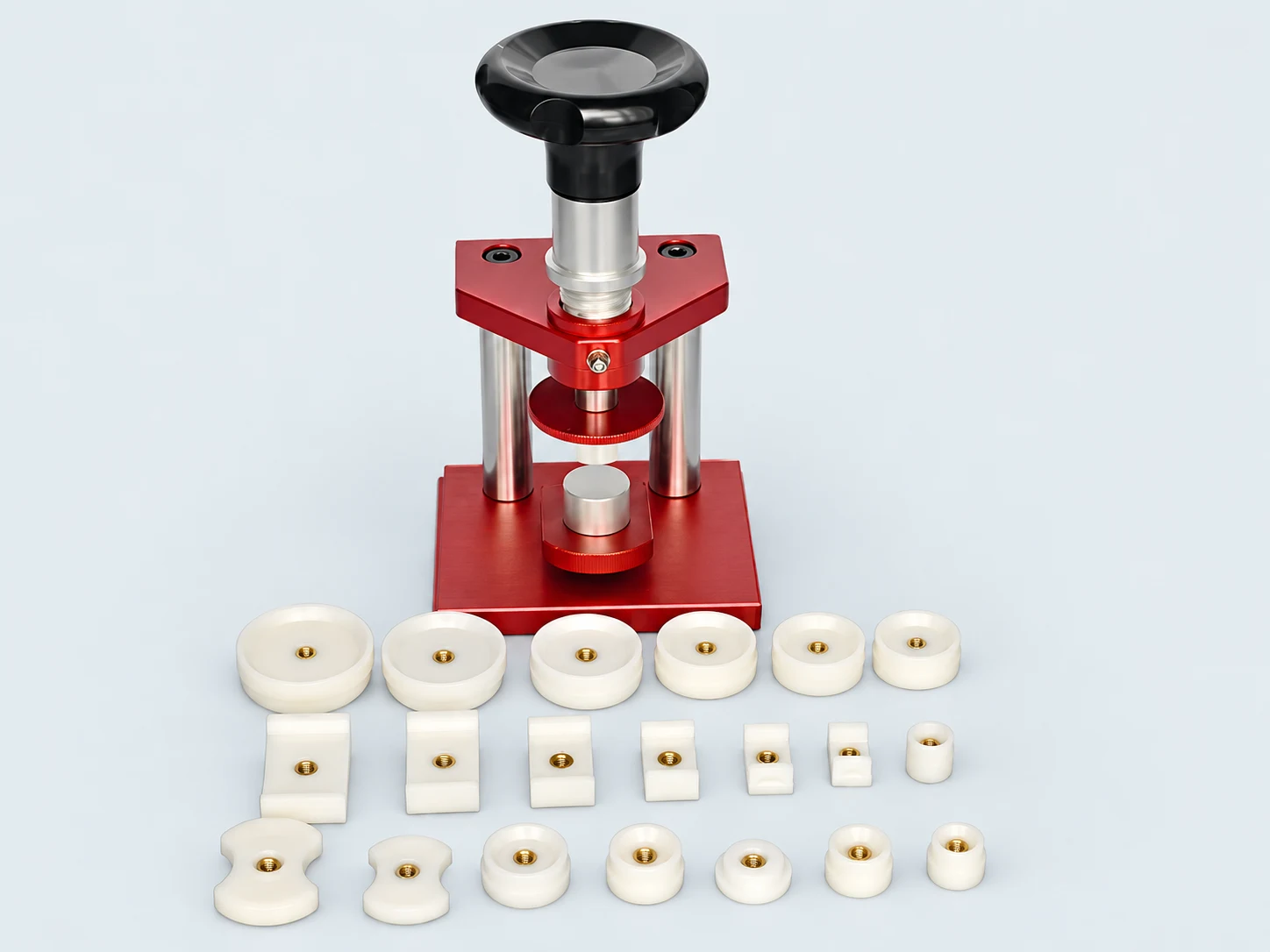 Red screw-down watch press with white nylon dies on a light gray background